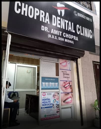 Storefront of Chopra Dental Clinic with a large black sign and posters showing dental services.